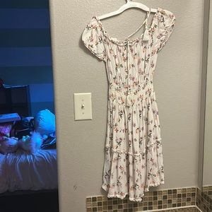 A beautiful flower filled white dress with curvy detail at bottom.